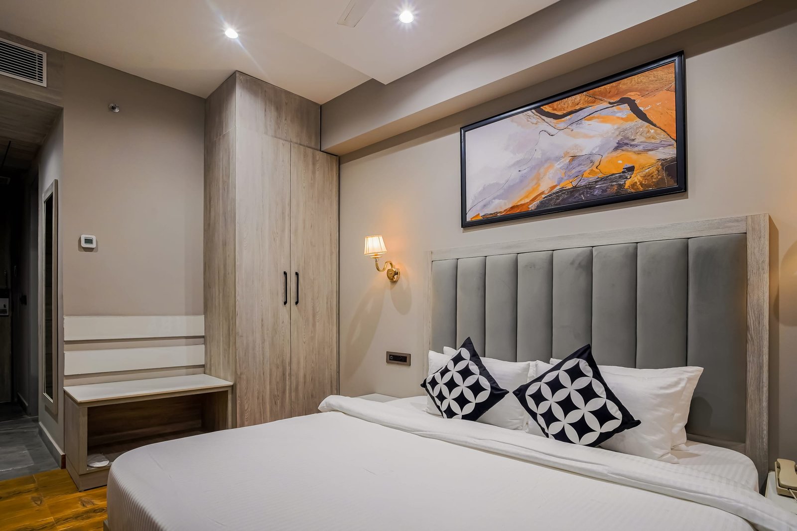 Guest room with an upholstered headboard and a wall-mounted television