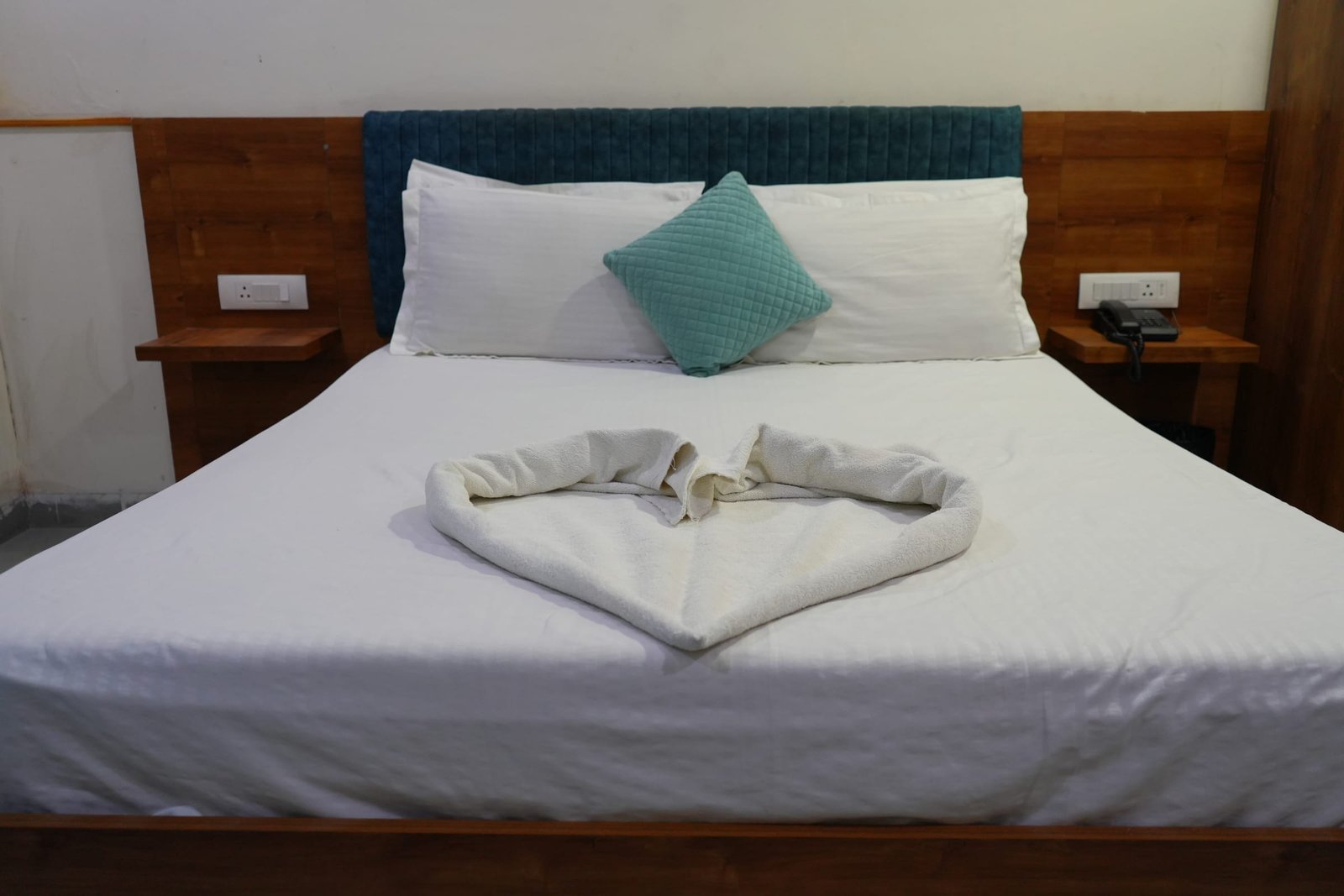 Twin pillows and a folded towel on a made bed