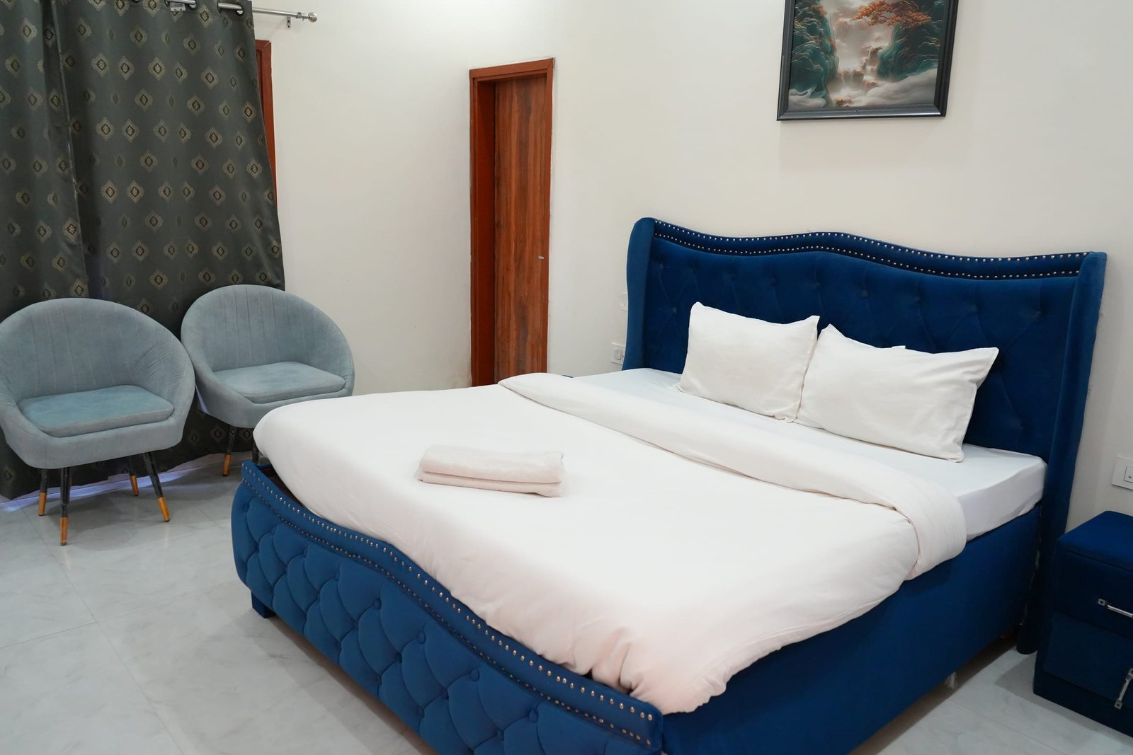 A suite with a deep blue upholstered bed