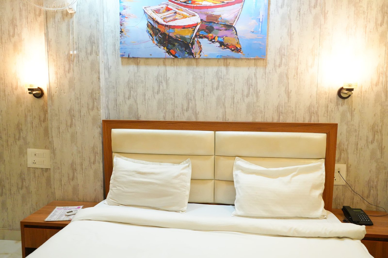 A made double bed beneath the boat painting