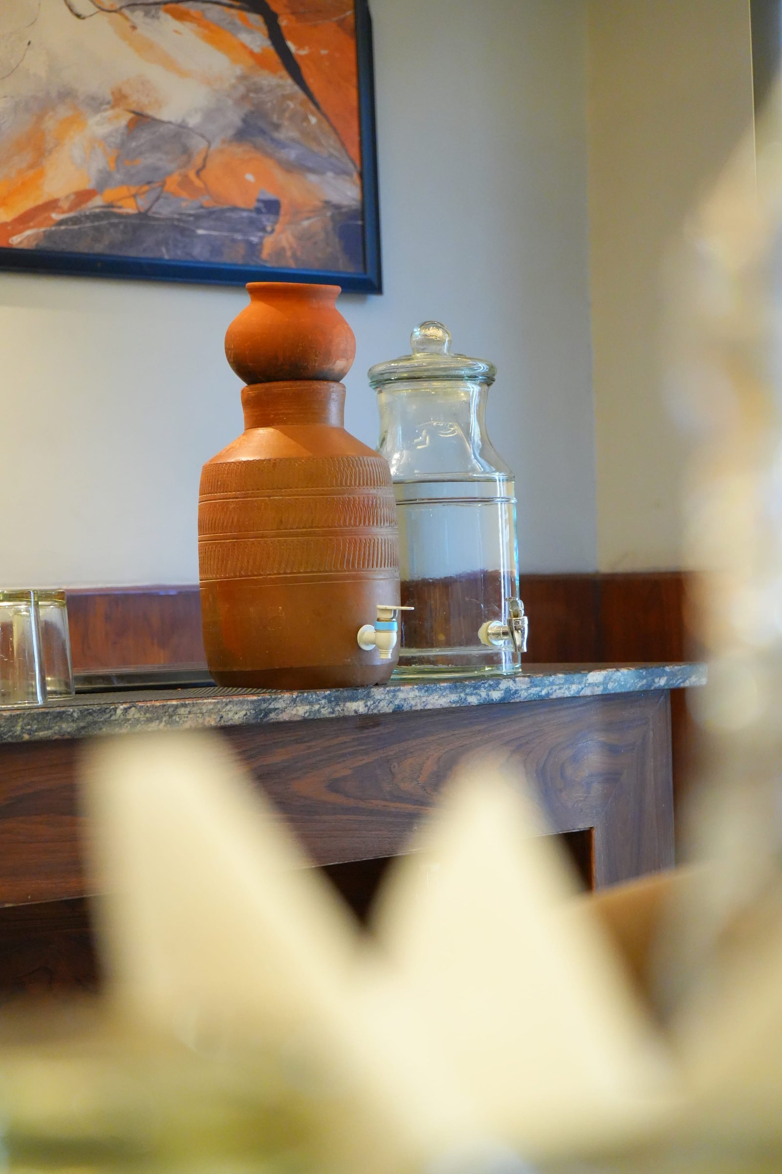 A terracotta water pot and glass dispenser on the counter